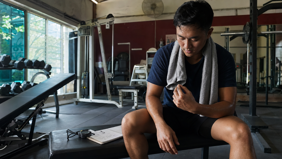 Sweaty athlete reviews a workout log after training in a neighborhood gym.